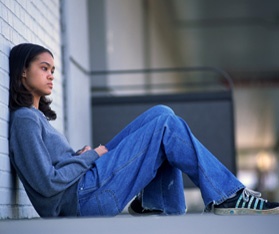 a woman sitting on the ground next to a white brick wall