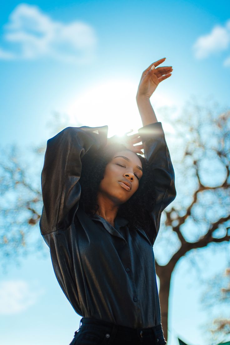 a woman with her hands up in the air, wearing a black shirt and jeans