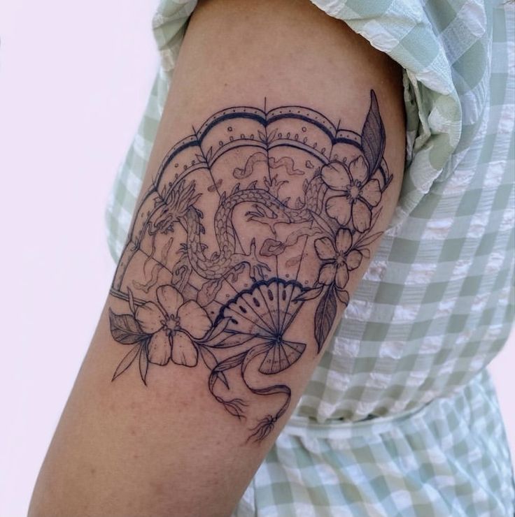 a woman's arm with a tattoo on it that has flowers and an umbrella