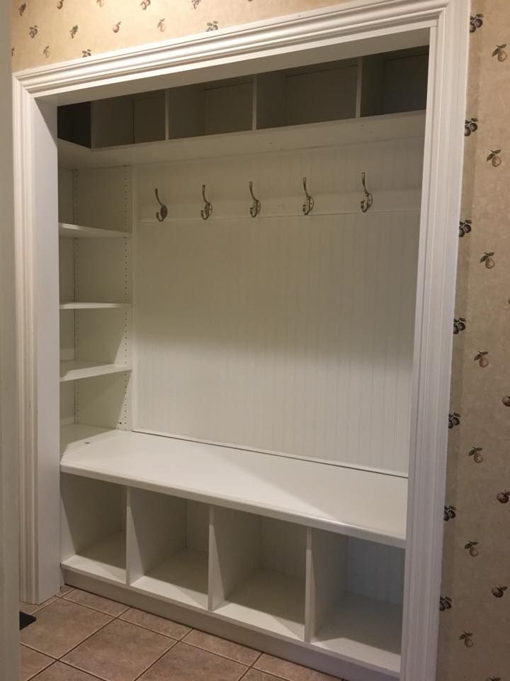 an empty white closet with shelves and hooks on the wall next to a tiled floor