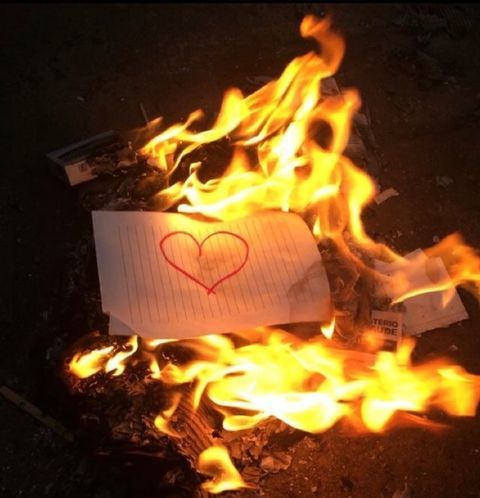 a piece of paper with a heart drawn on it sitting in the middle of fire