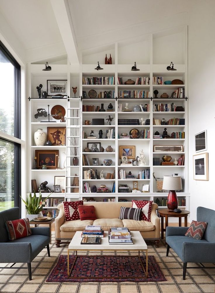 a living room filled with furniture and bookshelves next to a large glass window