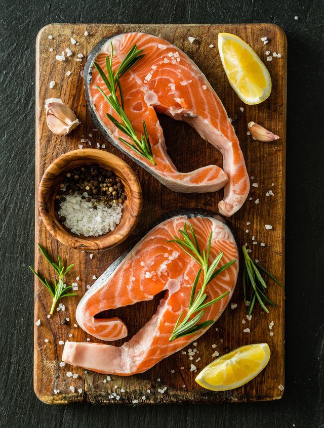 two raw salmons on a wooden cutting board with garlic and lemon