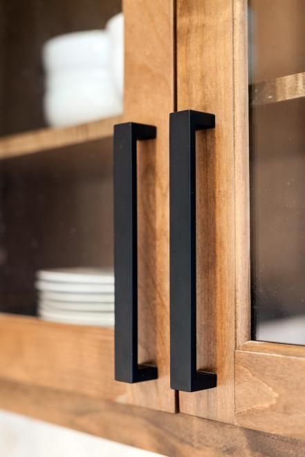 a wooden cabinet with glass doors and black handles