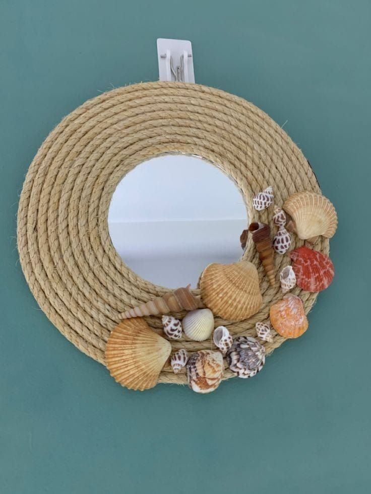 a rope wreath with seashells and shells hanging on the side of a wall