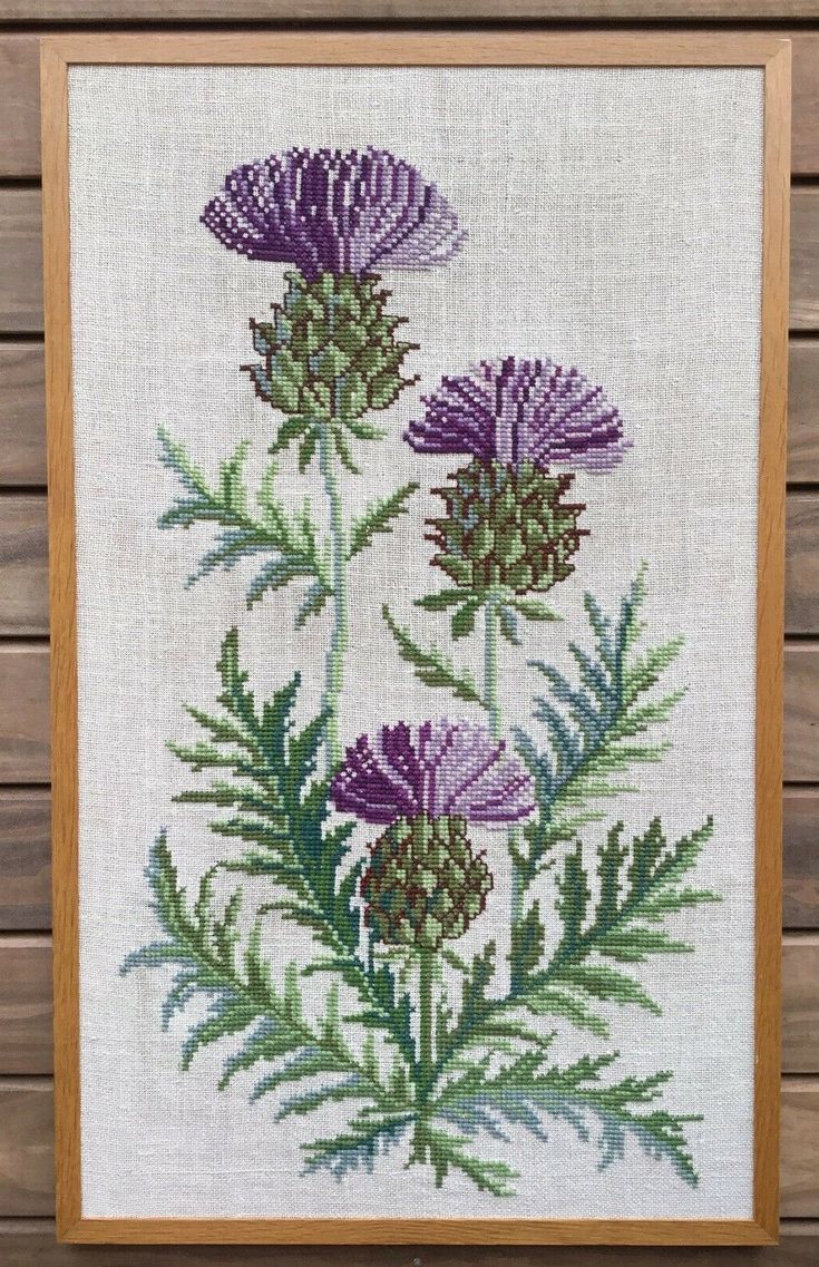 a cross stitch picture with purple flowers and green leaves