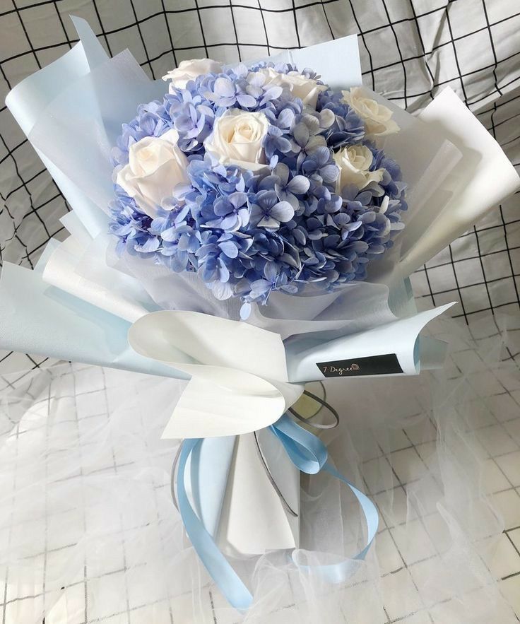 a bouquet of blue and white flowers is wrapped in plastic