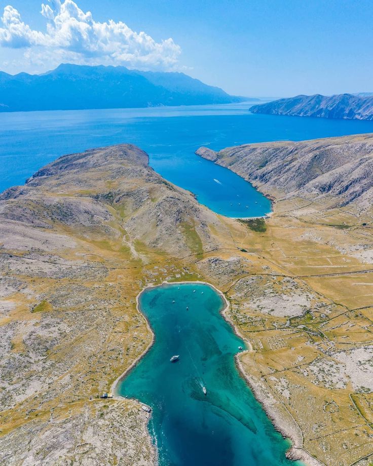 an aerial view of the water and land surrounding it, with mountains in the background