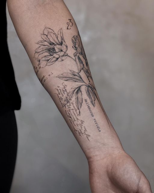 a person with a tattoo on their arm holding onto a hand that has flowers and writing on it