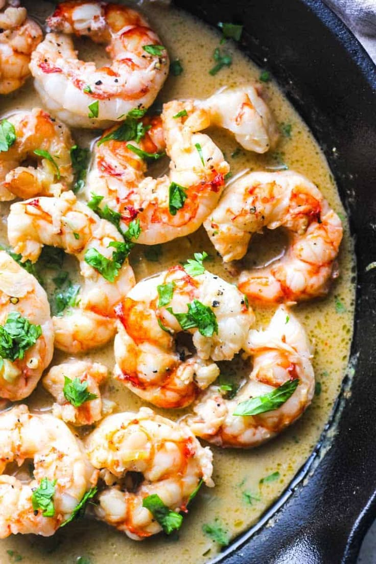 a skillet filled with cooked shrimp and garnished with parsley