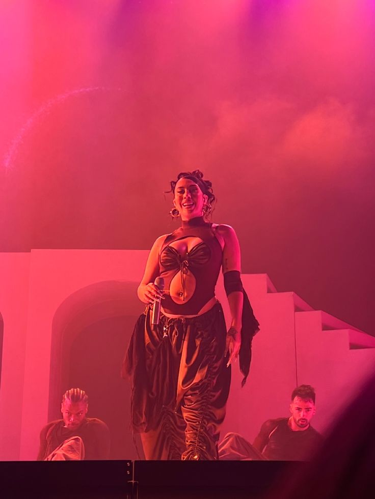 a woman standing on top of a stage wearing a dress and holding a frisbee