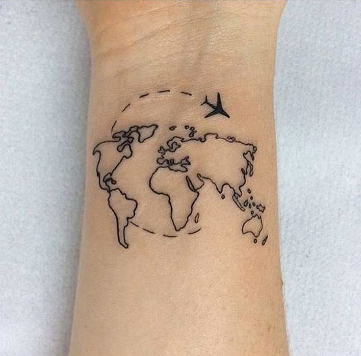 a small wrist tattoo with a world map and birds flying around the globe on it