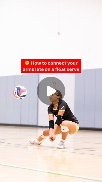 a woman in black shirt and yellow shorts playing volleyball on court with red sign that says how to connect your arms late on a float serve