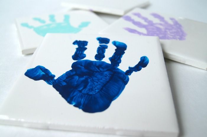 three handprints on white tiles with blue and purple ink