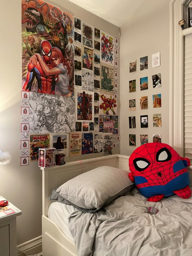 a bed with a spiderman pillow on top of it next to a wall full of comic books