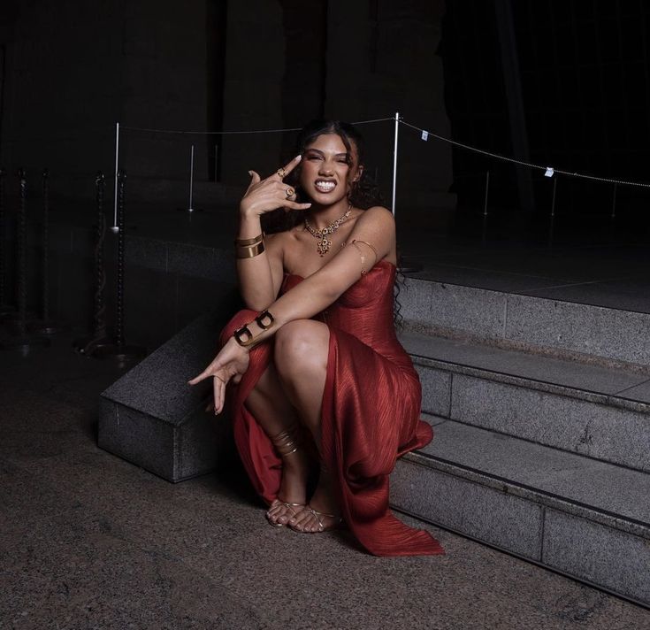 a woman in a red dress sitting on some steps