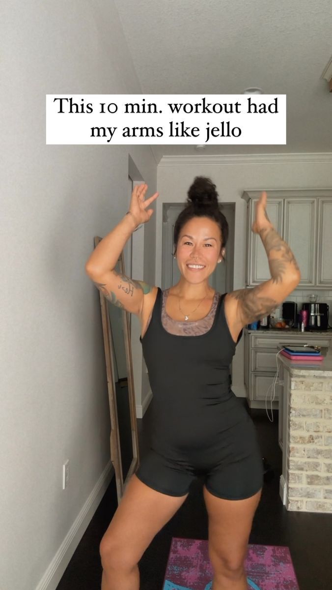 a woman standing on top of a yoga mat with her arms in the air while holding up