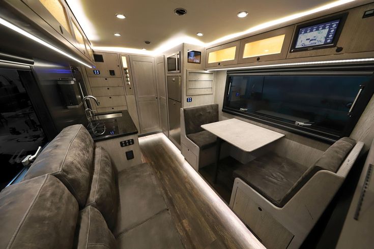 the interior of a bus with couches, tables and televisions on each side