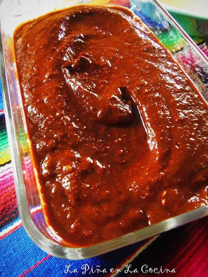 a glass dish filled with sauce on top of a colorful table cloth