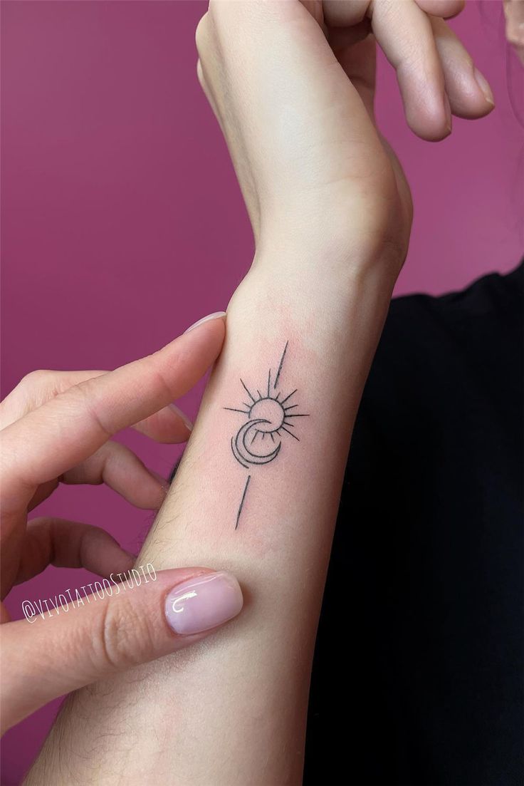 a woman's arm with a small sun and moon tattoo on the left wrist