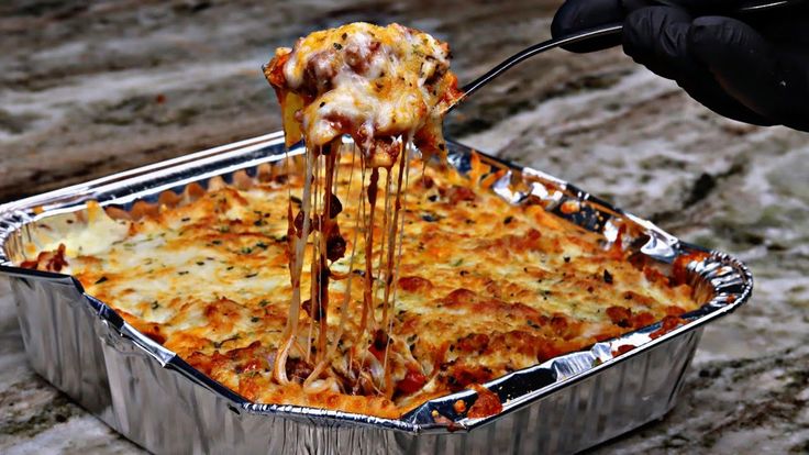 a person is taking a slice of lasagna casserole out of the pan