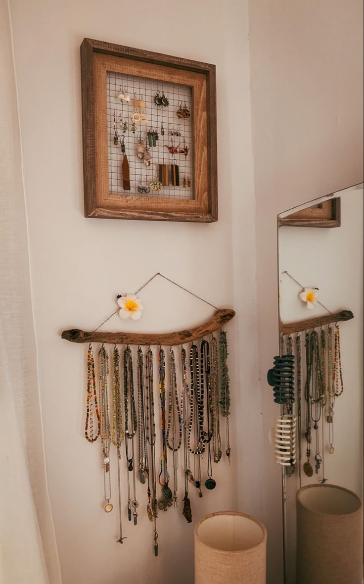 a mirror and some jewelry hanging on the wall next to a table with a lamp