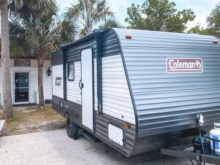 a trailer parked in front of a palm tree lined house with the word colemans on it