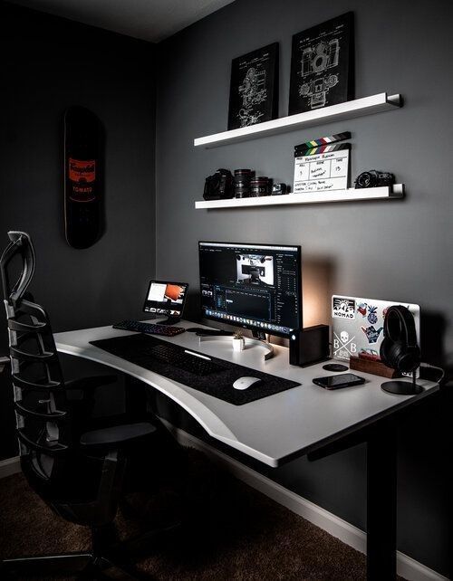 a desk with a computer on top of it in front of two shelves filled with pictures