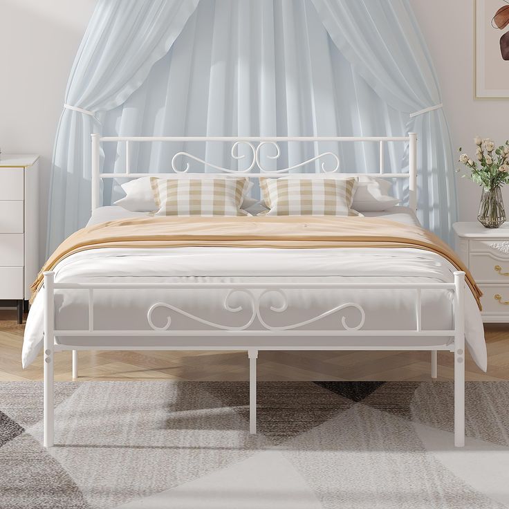 a white metal bed sitting in a bedroom on top of a carpeted floor next to a window