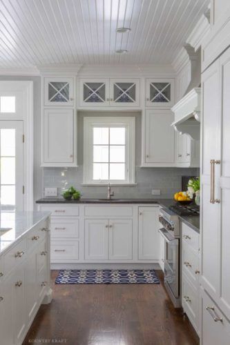 a kitchen with white cabinets and wood floors