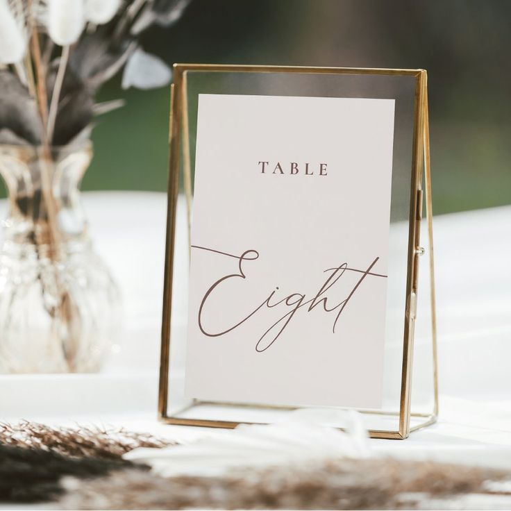 a table with a card holder and flowers in a vase