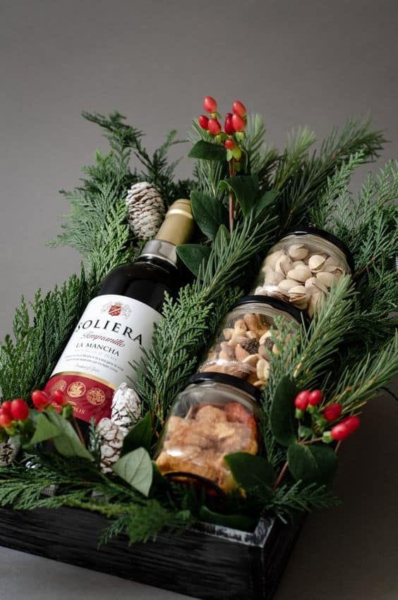 two bottles of wine sitting on top of a wooden box filled with nuts and greenery