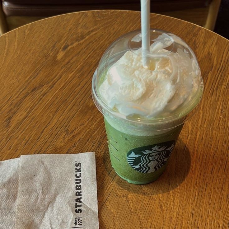 a starbucks drink with whipped cream in it on a table next to a paper napkin