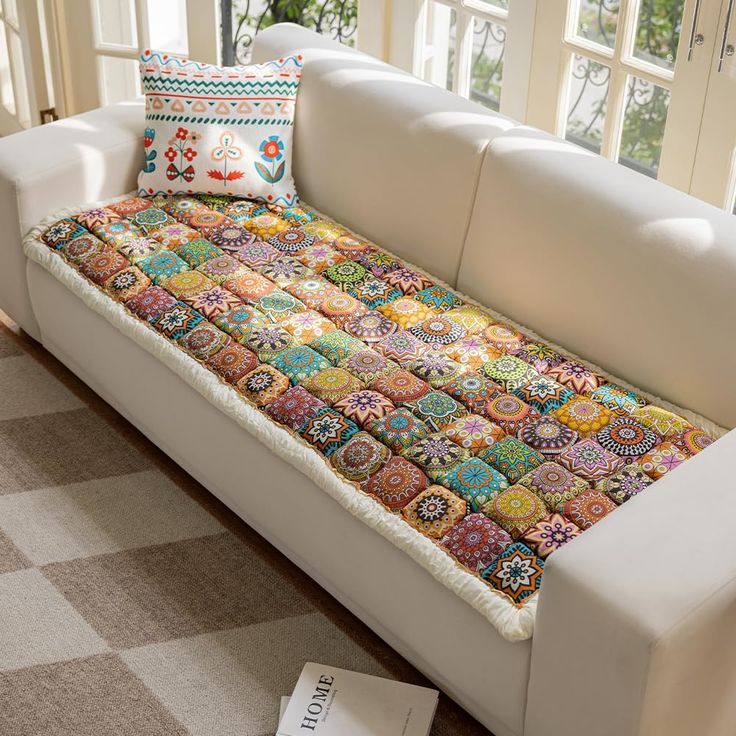 a white couch with colorful pillows on it in a living room next to a window