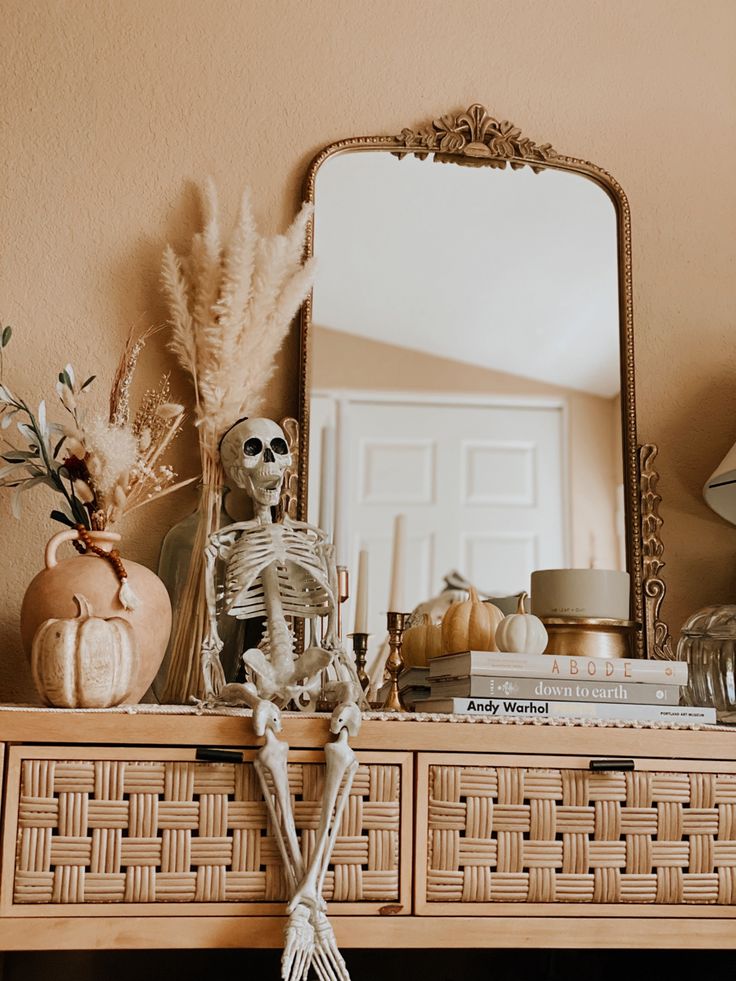 a skeleton sitting on top of a wooden dresser next to a mirror and vases