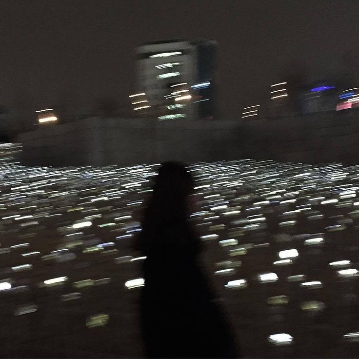 a person standing in the middle of a field full of cell phone phones at night