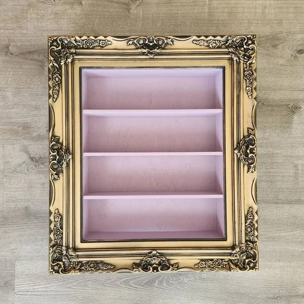 a gold frame with pink shelves in it