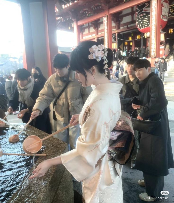 a group of people standing next to each other in front of a water fountain with wooden spoons