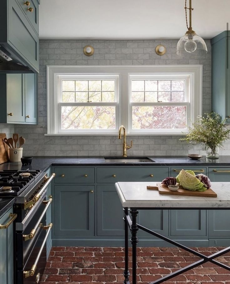 a kitchen with blue cabinets and brick flooring