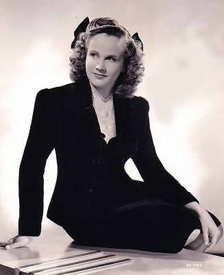 an old photo of a woman sitting on the floor with her legs crossed and wearing a cat ears hat