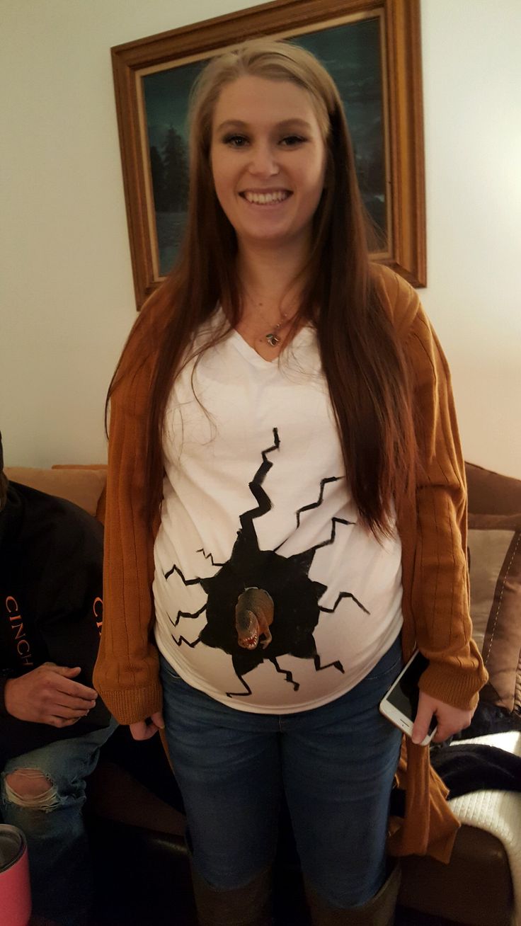 a woman standing in front of a couch holding a cell phone and smiling at the camera