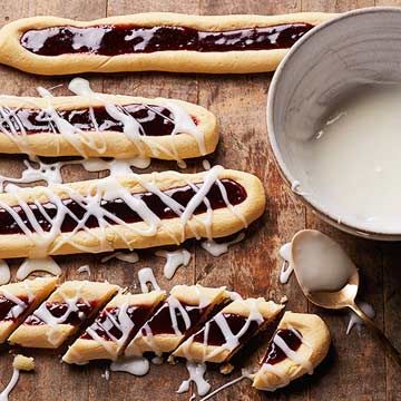 hot dogs with icing on them sitting next to a bowl of milk and spoons