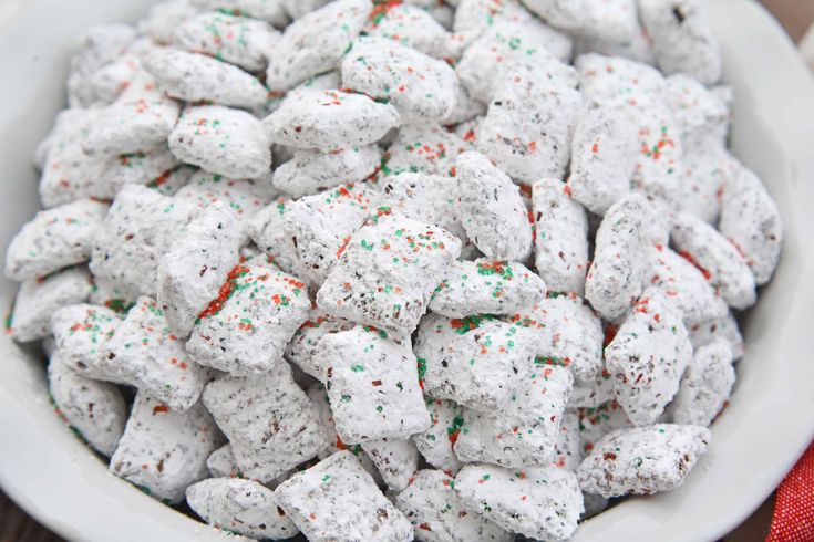 a white bowl filled with marshmallows and sprinkles on top of a wooden table