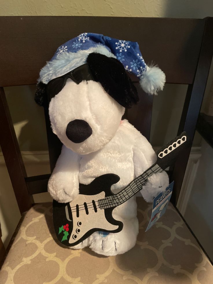 a stuffed dog with a guitar in its's lap and wearing a blue hat