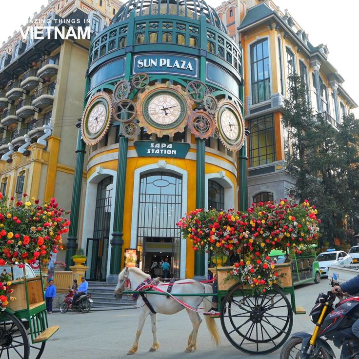 a horse drawn carriage in front of a building with clocks on it's sides