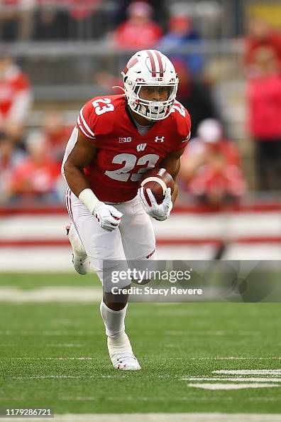 a football player running with the ball in his hand and people watching from the stands behind him