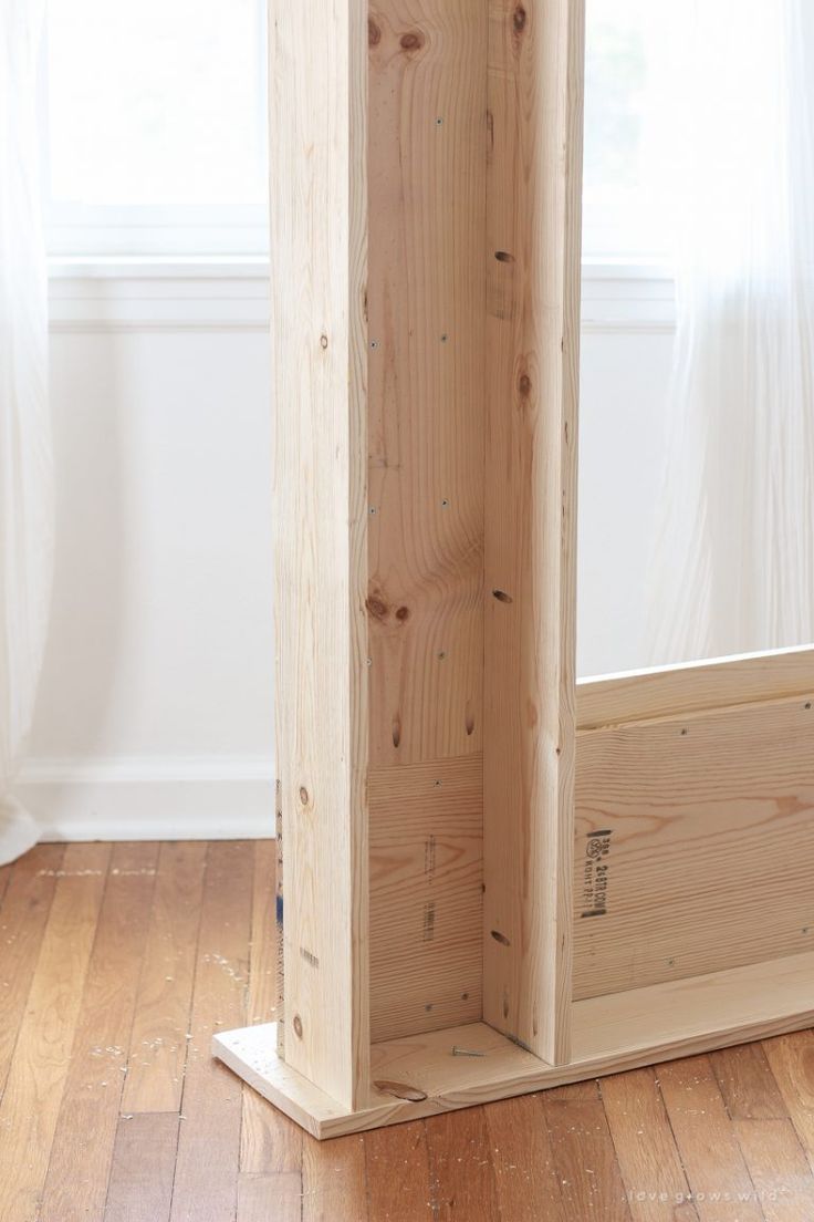 an empty wooden box sitting on top of a hard wood floor next to a window