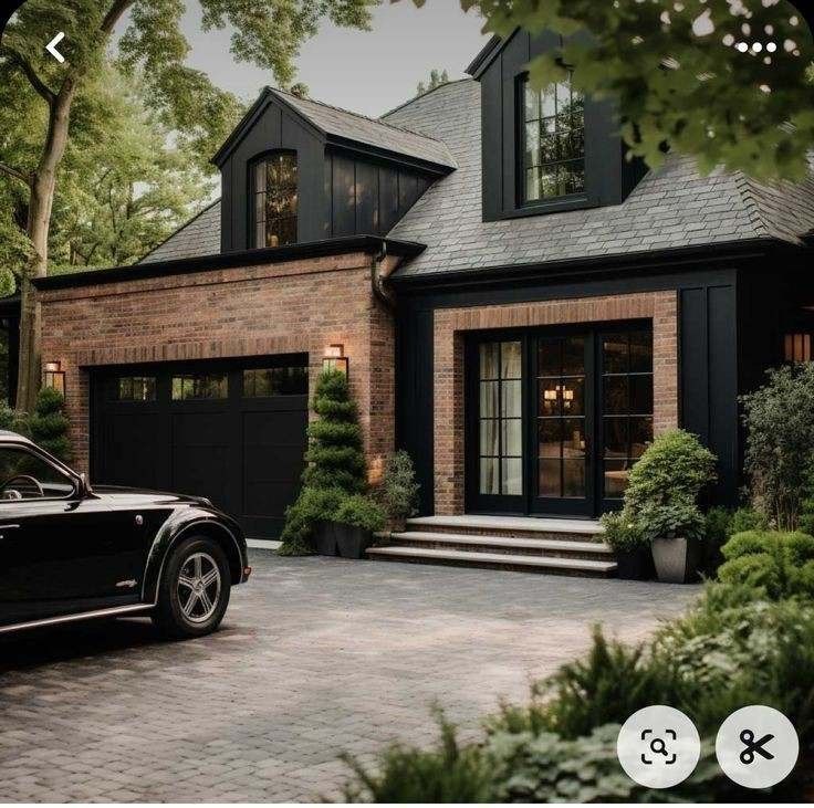 a black car is parked in front of a brick house with large windows and doors