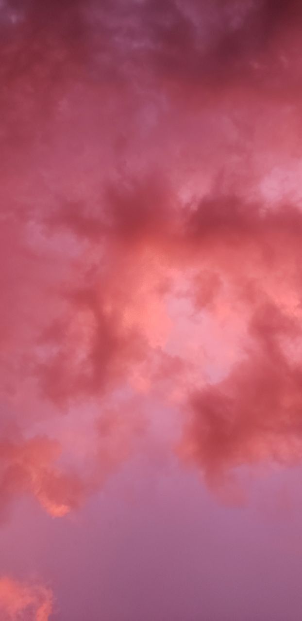 an airplane is flying in the sky with pink and purple clouds behind it at sunset