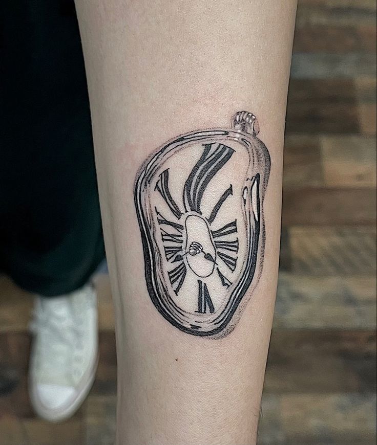 a small clock tattoo on the leg